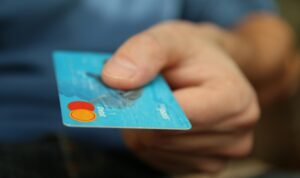 A close-up shot of a hand offering a blue debit card for payment.